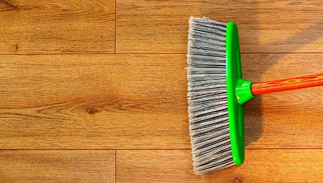 cleaning brown wooden floor with a broom | Floor Systems