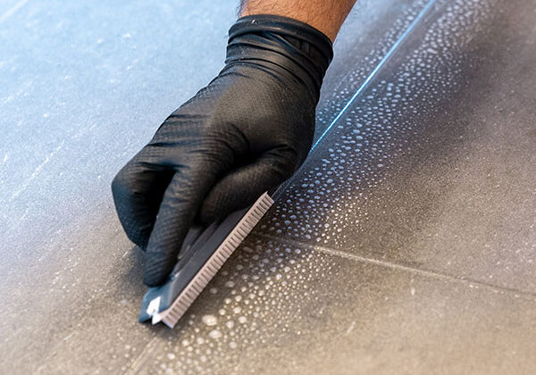 Professional cleaner cleaning grout with a brush blade | Floor Systems